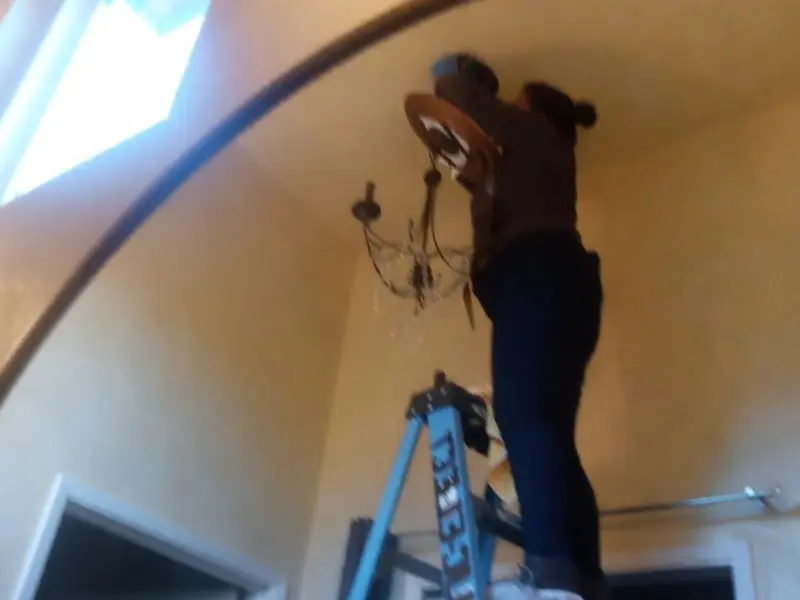 Electrician installing a chandelier in a Springfield residence